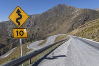 yellow sign on road that says a curve to go ahead on it in mountainous area