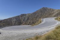 a man is riding his bike up a curved road in the mountains with no cars