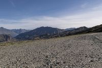 a desert area with rocks and a bike in the middle with mountains in the background