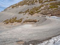 the winding road on the hill is made up by a stone wall and snow in a mountainous area