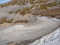 the winding road on the hill is made up by a stone wall and snow in a mountainous area