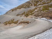 the winding road on the hill is made up by a stone wall and snow in a mountainous area