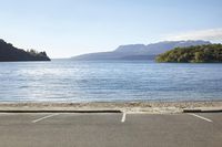 a boat docked next to the edge of a lake with mountains in the distance and a bridge near the end