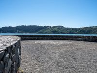 there is an outside area with a stone wall and a large hill on the side