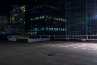 a empty parking lot next to a group of tall buildings in the city at night