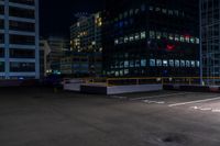 a empty parking lot next to a group of tall buildings in the city at night