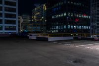 a empty parking lot next to a group of tall buildings in the city at night