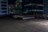 a empty parking lot next to a group of tall buildings in the city at night