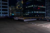 a empty parking lot next to a group of tall buildings in the city at night