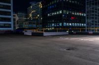 a empty parking lot next to a group of tall buildings in the city at night