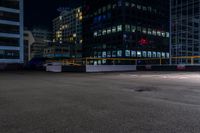 a empty parking lot next to a group of tall buildings in the city at night