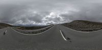 a curved road winding through the mountains under a cloudy sky at a curve as seen from below