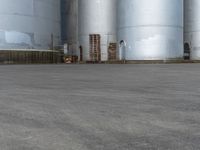 a skateboarder is doing tricks on a cement surface near a silos in an urban setting