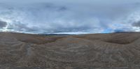 the cloudy clouds are rising over the barren hills in the foreground, and the horizon is blurry