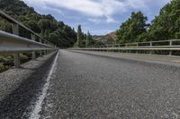 a long, empty highway with two yellow arrows on it and trees in the background