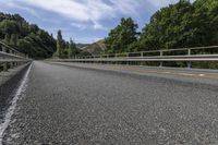 a long, empty highway with two yellow arrows on it and trees in the background