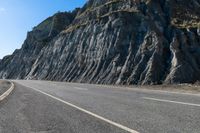 a motorcycle is traveling past the cliffs on a sunny day for a ride down to the beach