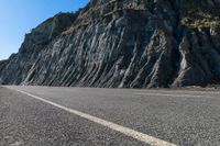 a motorcycle is traveling past the cliffs on a sunny day for a ride down to the beach