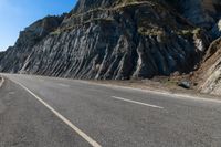 a motorcycle is traveling past the cliffs on a sunny day for a ride down to the beach