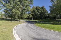 an empty road with a curved curve going up into the trees on each side of it