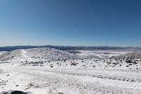 an over the shoulder view of snow covered mountains with rock, rock and snow piled on top