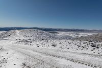 an over the shoulder view of snow covered mountains with rock, rock and snow piled on top