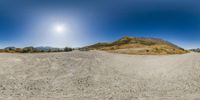 a spherical lens image of a dirt road with mountains in the distance in the background