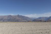 a desert area with rocks and a bike in the middle with mountains in the background