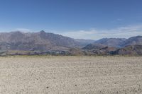 a desert area with rocks and a bike in the middle with mountains in the background