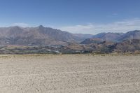 a desert area with rocks and a bike in the middle with mountains in the background