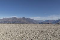 a desert area with rocks and a bike in the middle with mountains in the background