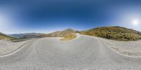 an overhead shot of the road and mountains in a 360 - spherical camera image, in full color