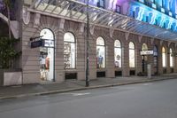 the corner of an empty building has windows lit with brightly lit lights on it's side