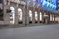 the corner of an empty building has windows lit with brightly lit lights on it's side