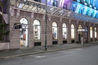 the corner of an empty building has windows lit with brightly lit lights on it's side