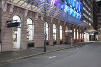 the corner of an empty building has windows lit with brightly lit lights on it's side