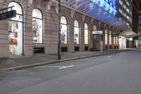 the corner of an empty building has windows lit with brightly lit lights on it's side