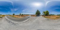 the camera panoramic view of a road with sheep grazing in the background and blue sky