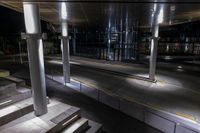 an empty bus station with traffic in it at night time with lights shining brightly on the glass windows