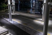 an empty bus station with traffic in it at night time with lights shining brightly on the glass windows