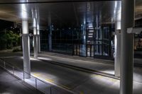 an empty bus station with traffic in it at night time with lights shining brightly on the glass windows