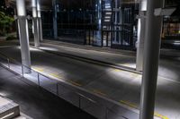 an empty bus station with traffic in it at night time with lights shining brightly on the glass windows