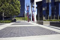 a red metal sculpture sits in front of several trees, and has many colors in it