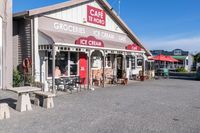 two stores on the side of a road with tables and chairs in front of them