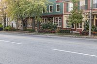 a very nice looking street with some shops on the street side and houses lined by trees