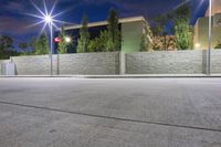 an empty parking lot with street lights and a stone building in the background at night