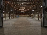 a large barn is lit up for dinner and event events with lights hanging from the ceiling