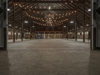 a large barn is lit up for dinner and event events with lights hanging from the ceiling