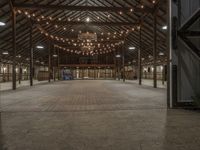 a large barn is lit up for dinner and event events with lights hanging from the ceiling