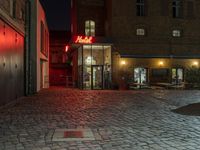 a bricked alley and a red neon sign are pictured in this photo and the buildings look to be empty